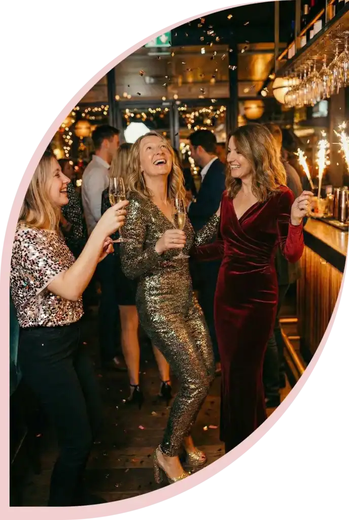 Frauen um die 40 feiern ausgelassen auf einer Party mit Sektgläsern und Wunderkerzen